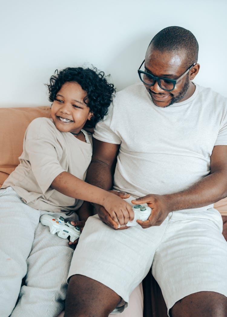 Cheerful Ethnic Kid Helping Father To Play Video Game