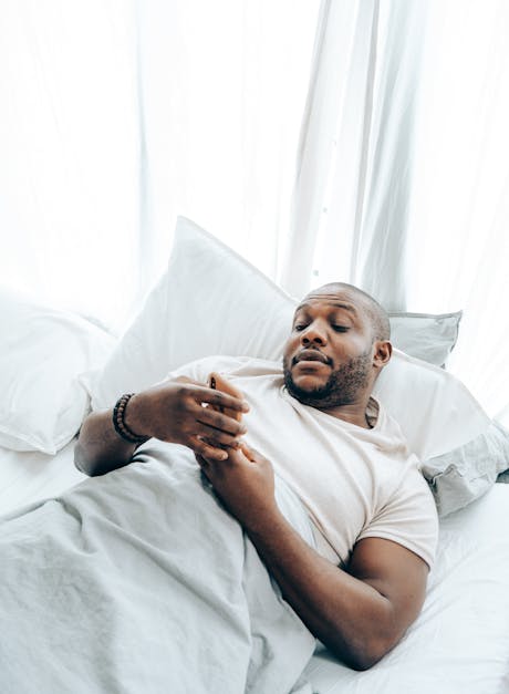 Adult Black Man Using Smartphone In Bed Free Stock Photo