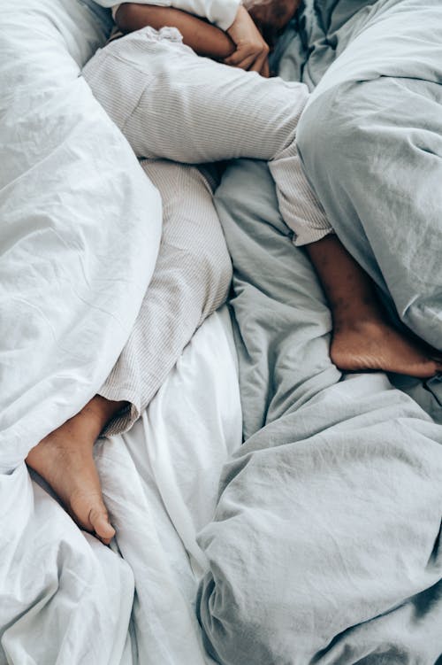 Free From above of crop unrecognizable person in pajama sleeping in comfortable soft bed Stock Photo