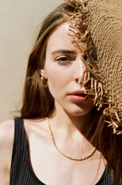 Free Elegant portrait of a woman wearing a straw hat, half her face hidden, showcasing minimalist fashion. Stock Photo