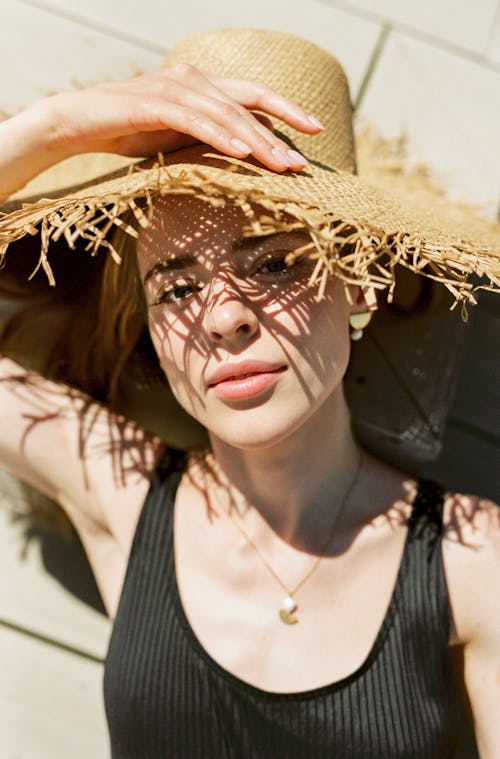 A Woman Wearing a Black Tank Top and a Straw Hat