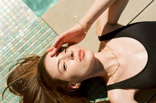 Woman in Black Tank Top Lying beside Swimming Pool