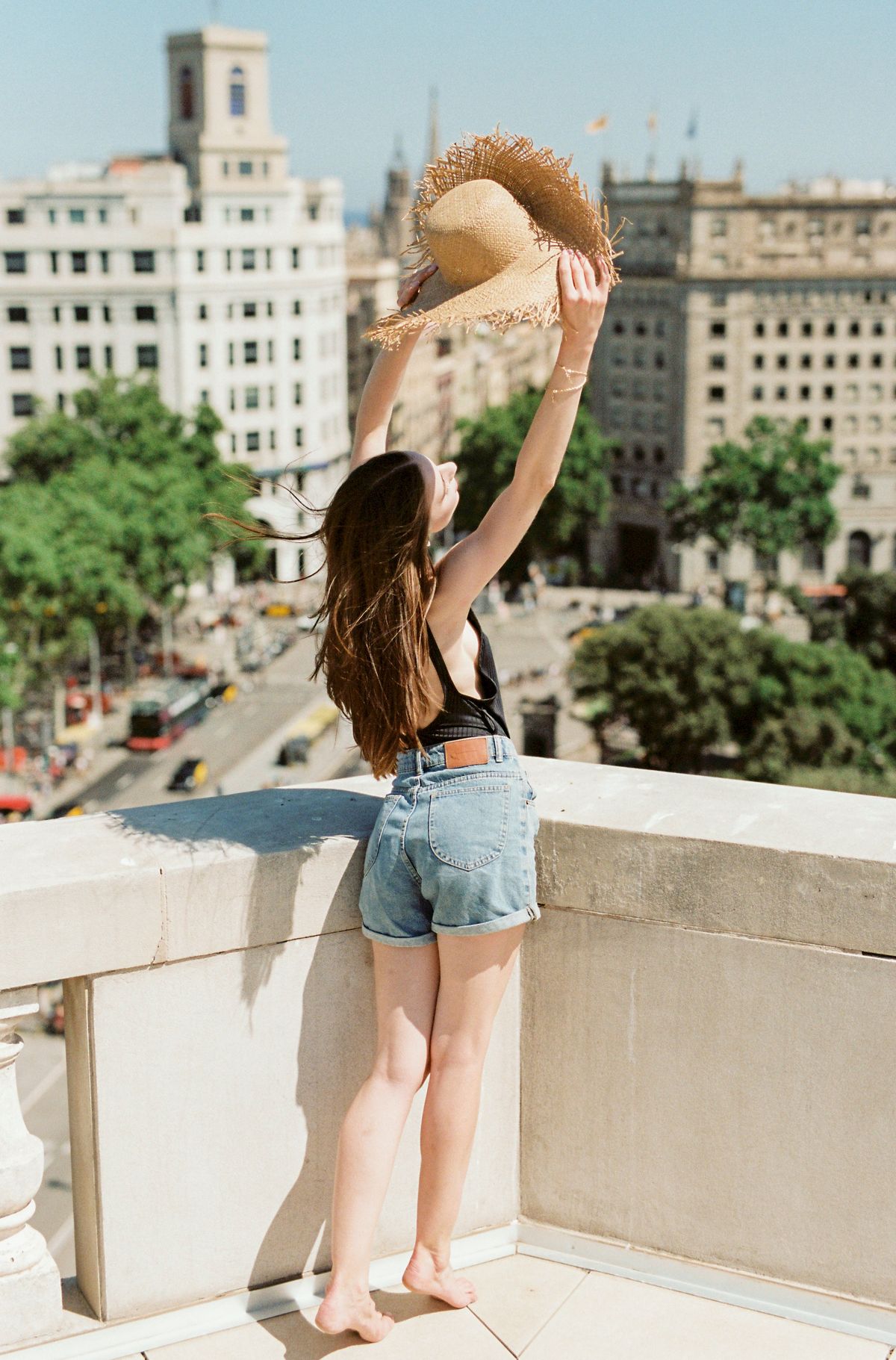 Woman in blue denim shorts on a rooftop — denim shorts outfit ideas for summer 2026