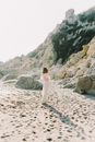 夏日沙滩上，一位金发碧眼的女子优雅地摆着姿势，与自然美景和宁静相映成趣