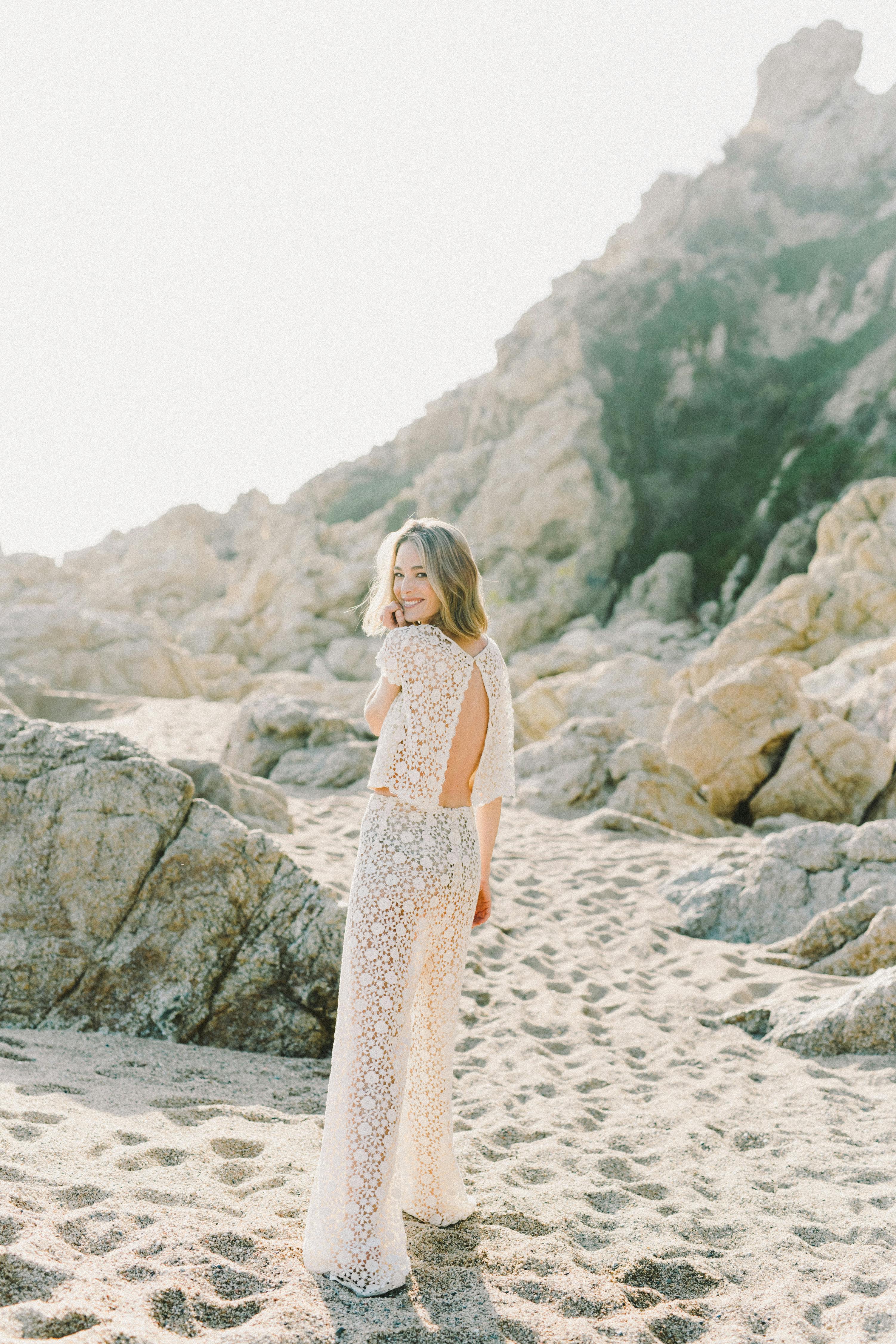 夏日里，一位穿着无背连衣裙的女人在岩石海滩上享受阳光明媚的日子