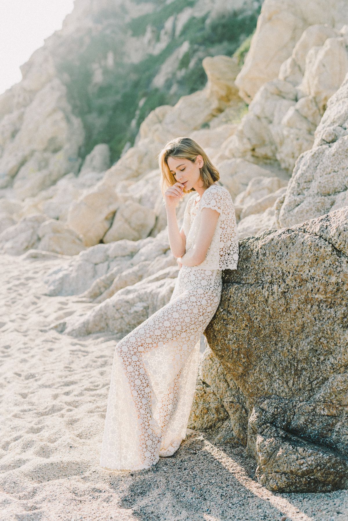 A woman in white lace beside a rock formation, the embellished resort showpiece