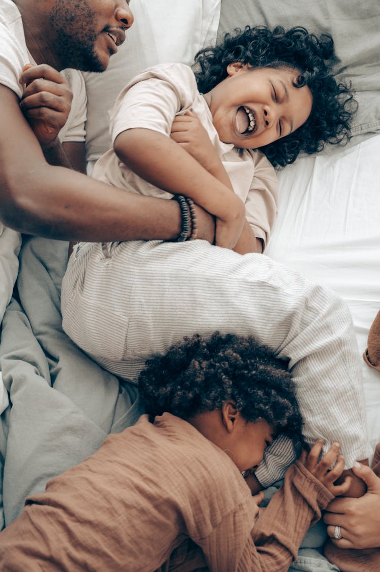 Cute Little Black Girls Laughing While Playing With Dad On Bed