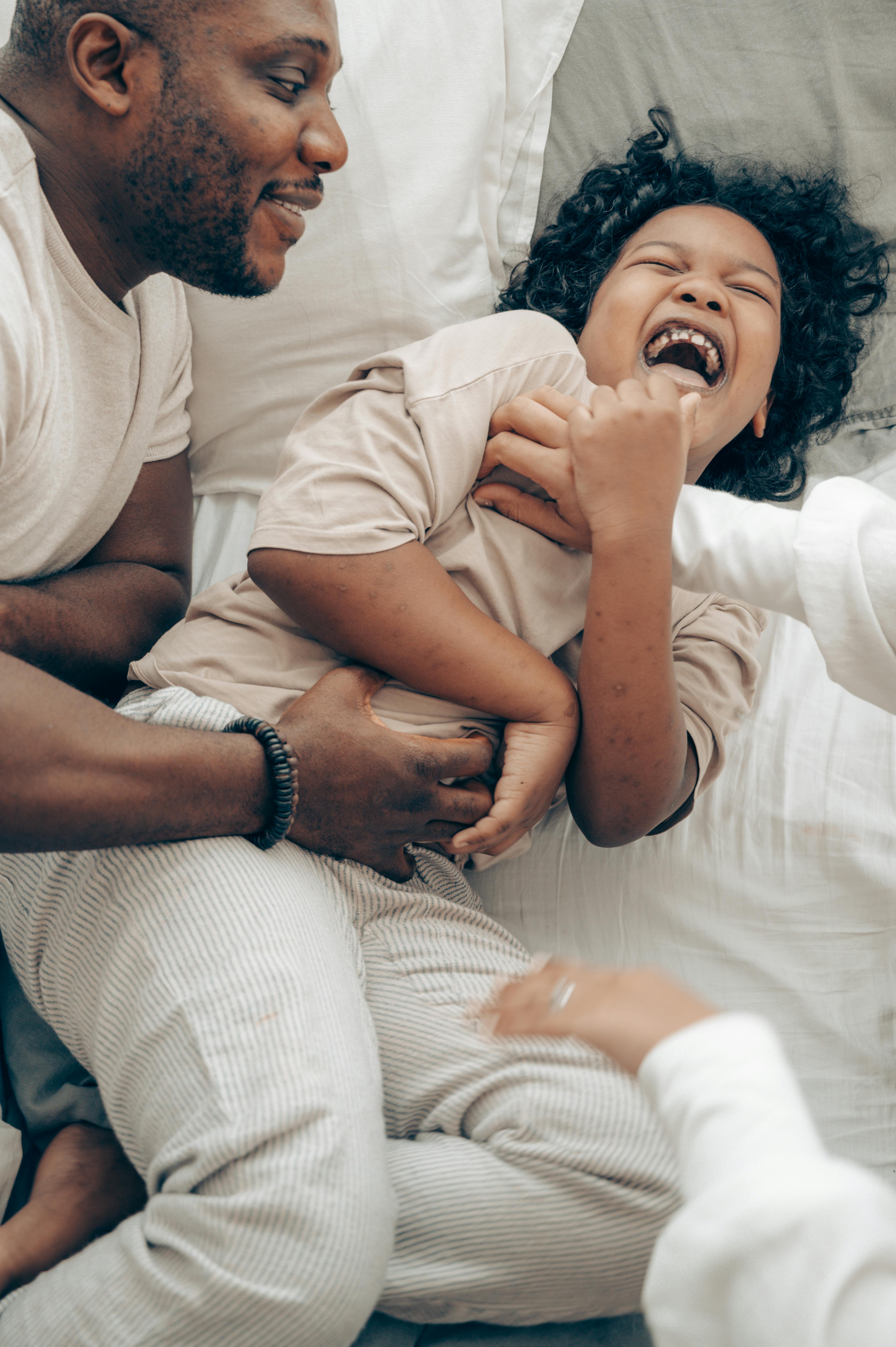 cute black kid laughing while playing with father