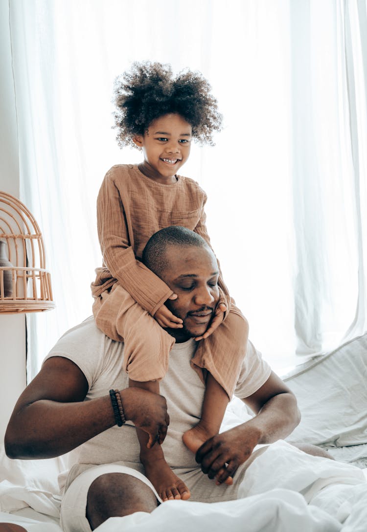 Happy Little Black Kid Sitting On Shoulders Of Dad