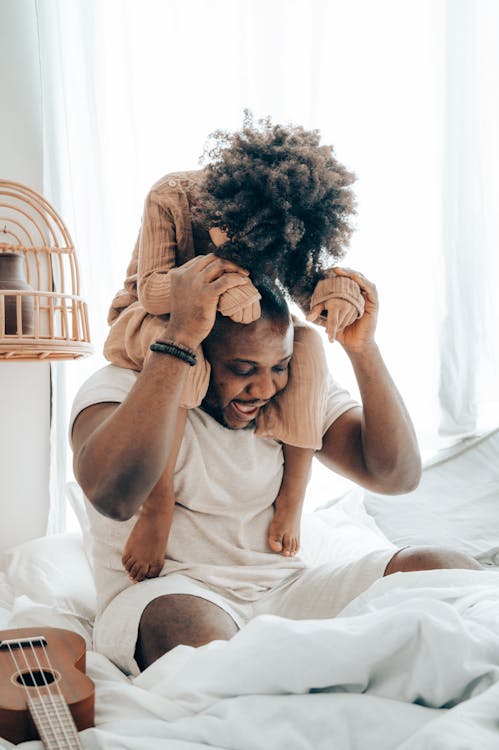 Free Happy ethnic male and child playing on bed Stock Photo