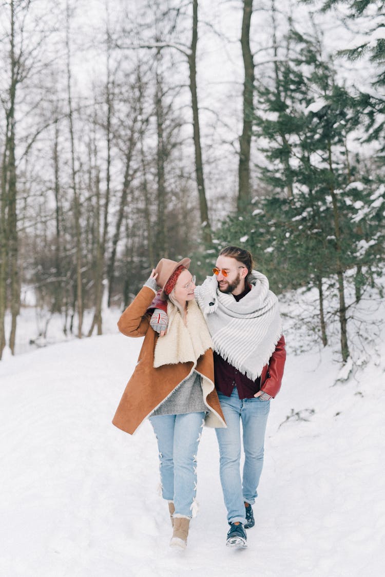 A Smiling Couple Walking In A Winter Forest