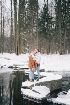 在宁静的冬季公园里，一对夫妇在白雪覆盖的河边拥抱