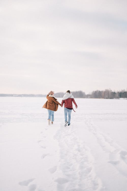 Free People Walking on Snow Covered Field Holding Hands Stock Photo