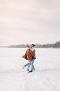 一对幸福的夫妇在白雪覆盖的冬日风景中相拥，展现着爱与快乐