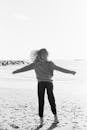 Woman in Long Sleeve Shirt Walking on Beach
