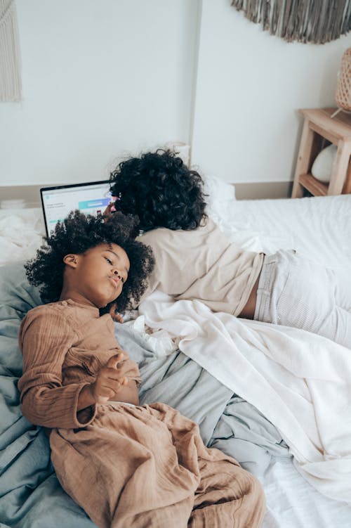 Kids lying on bed and browsing laptop