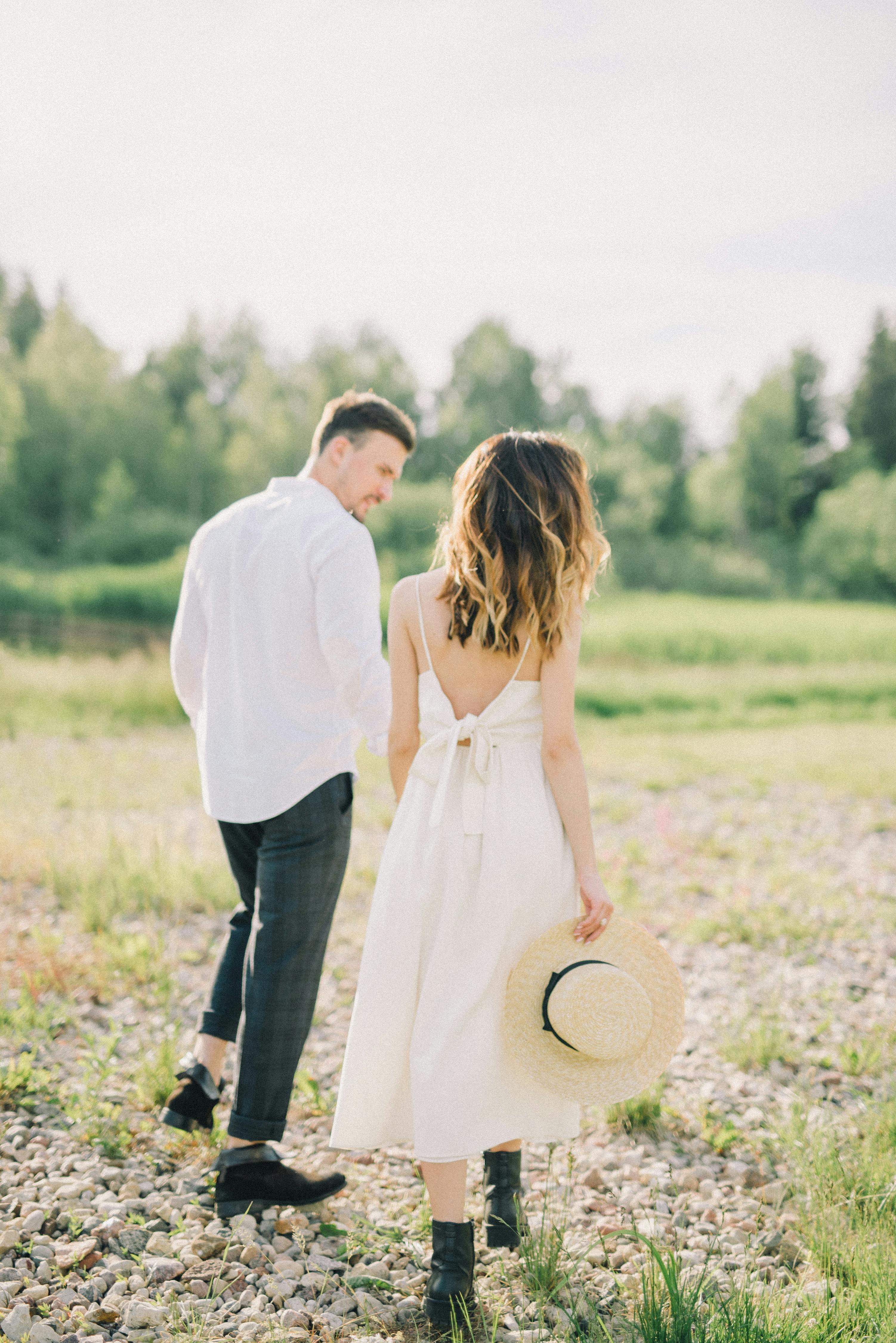 一对夫妇手牵手走过阳光普照的田野，空气中弥漫着浪漫与宁静