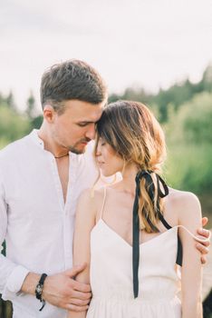 Couple embracing in a serene outdoor setting with soft light.
