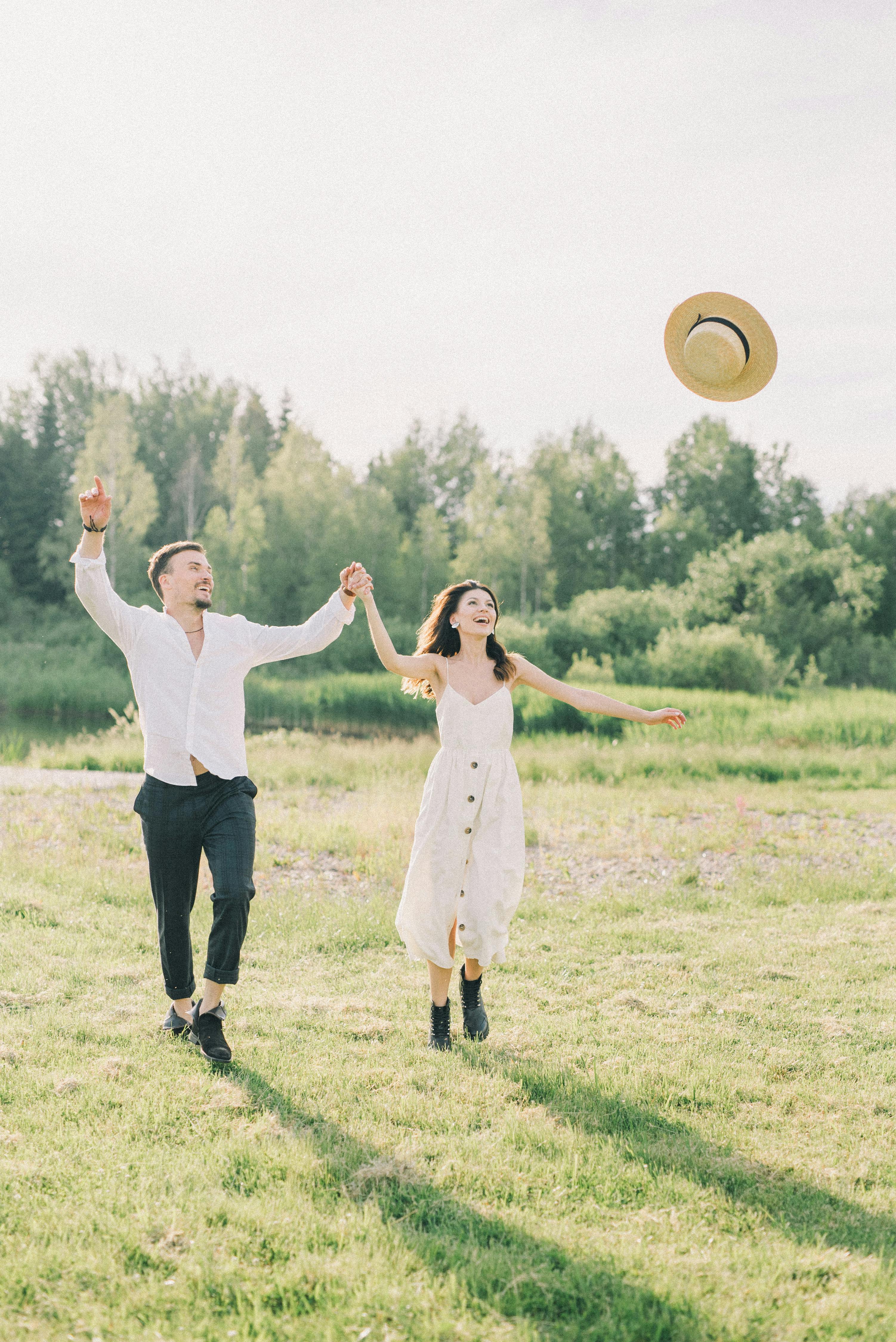 couple standing on green grass field laughing