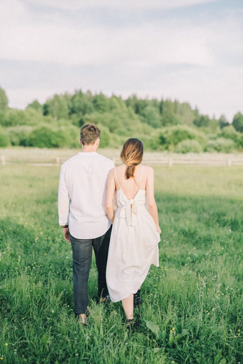 Couple Walking and Holding Hands on Field