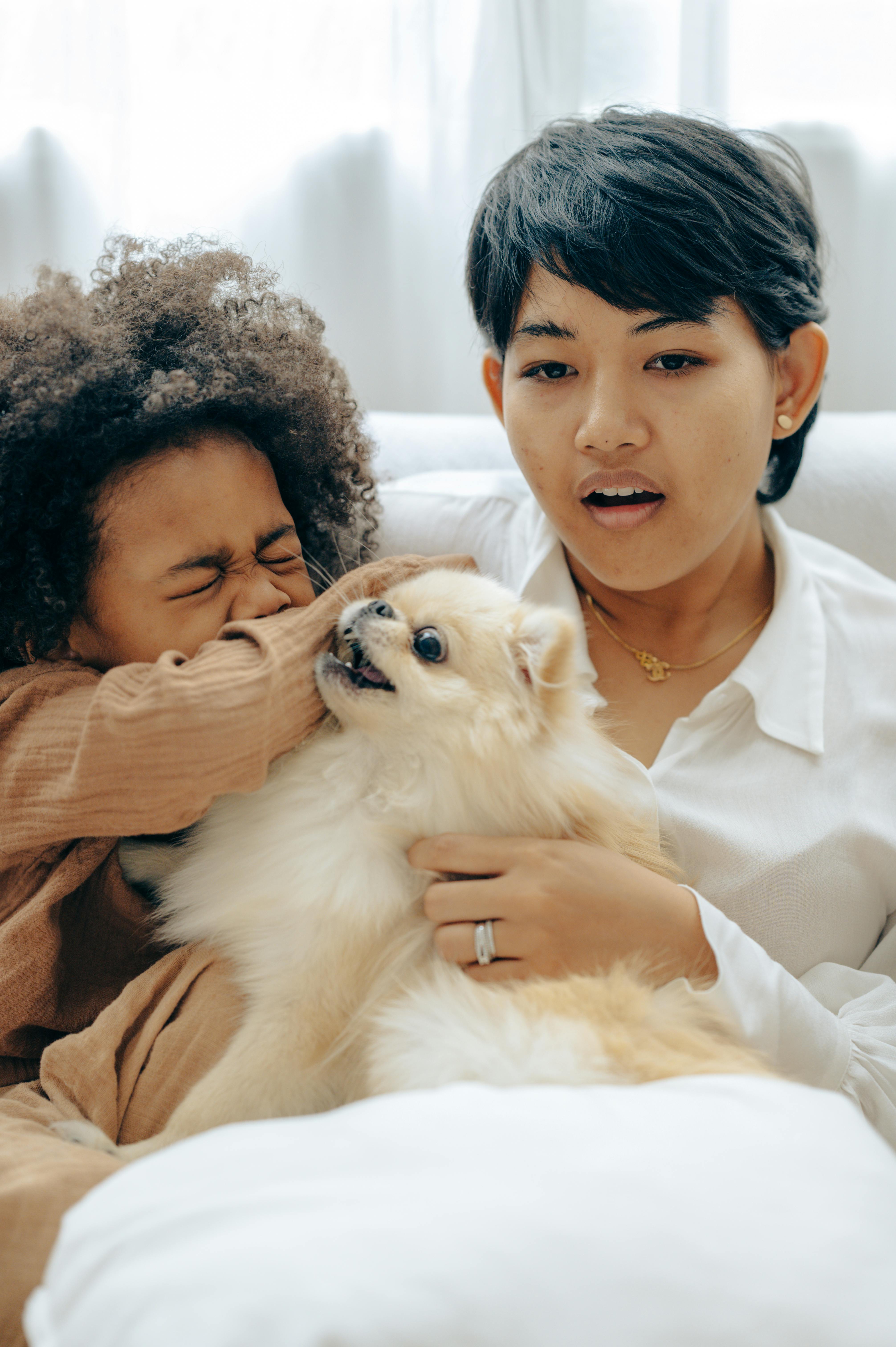 ethnic mother watching tv with kid playing with dog at home