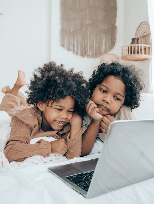 Happy and sad black brothers watching video on laptop