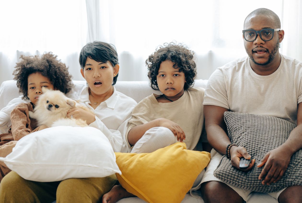 Família com cachorro aproveitando um filme na televisão