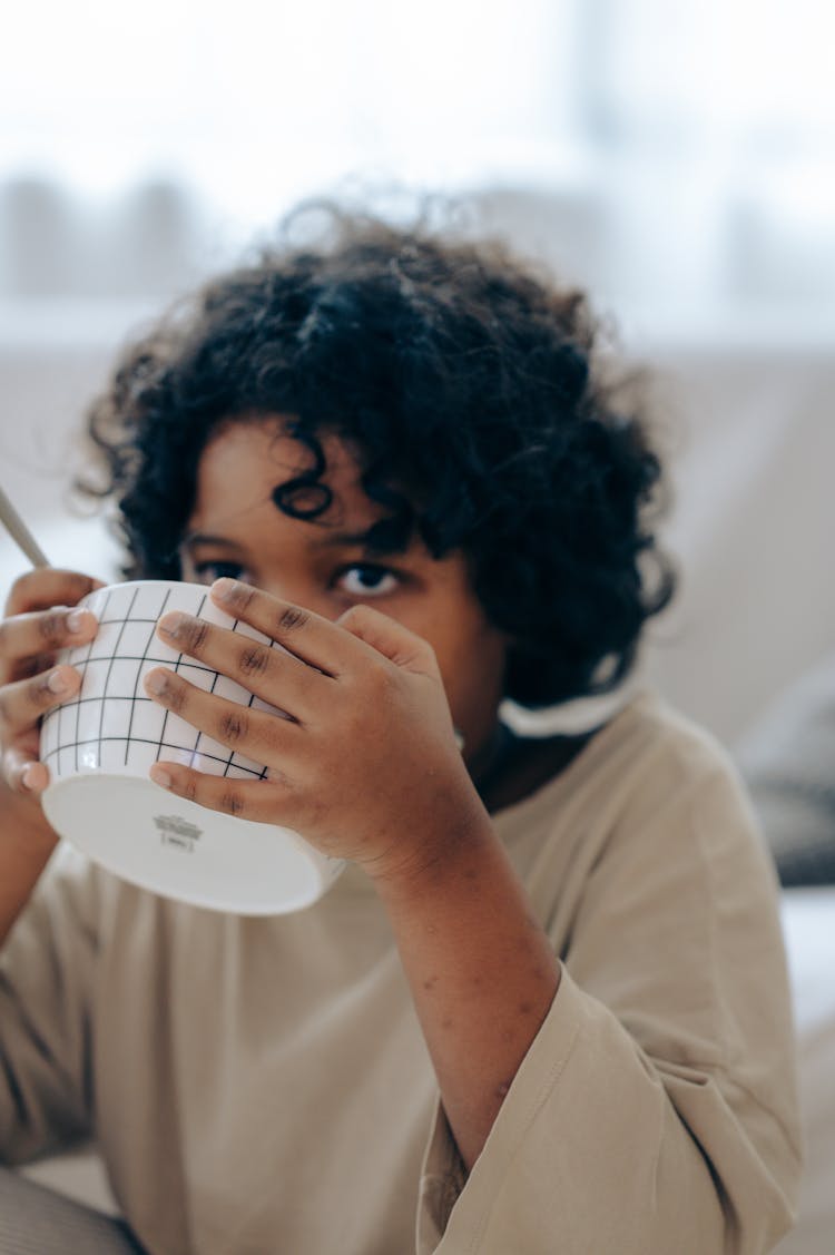 Adorable Black Child Drinking Bowl Of Milk In Morning