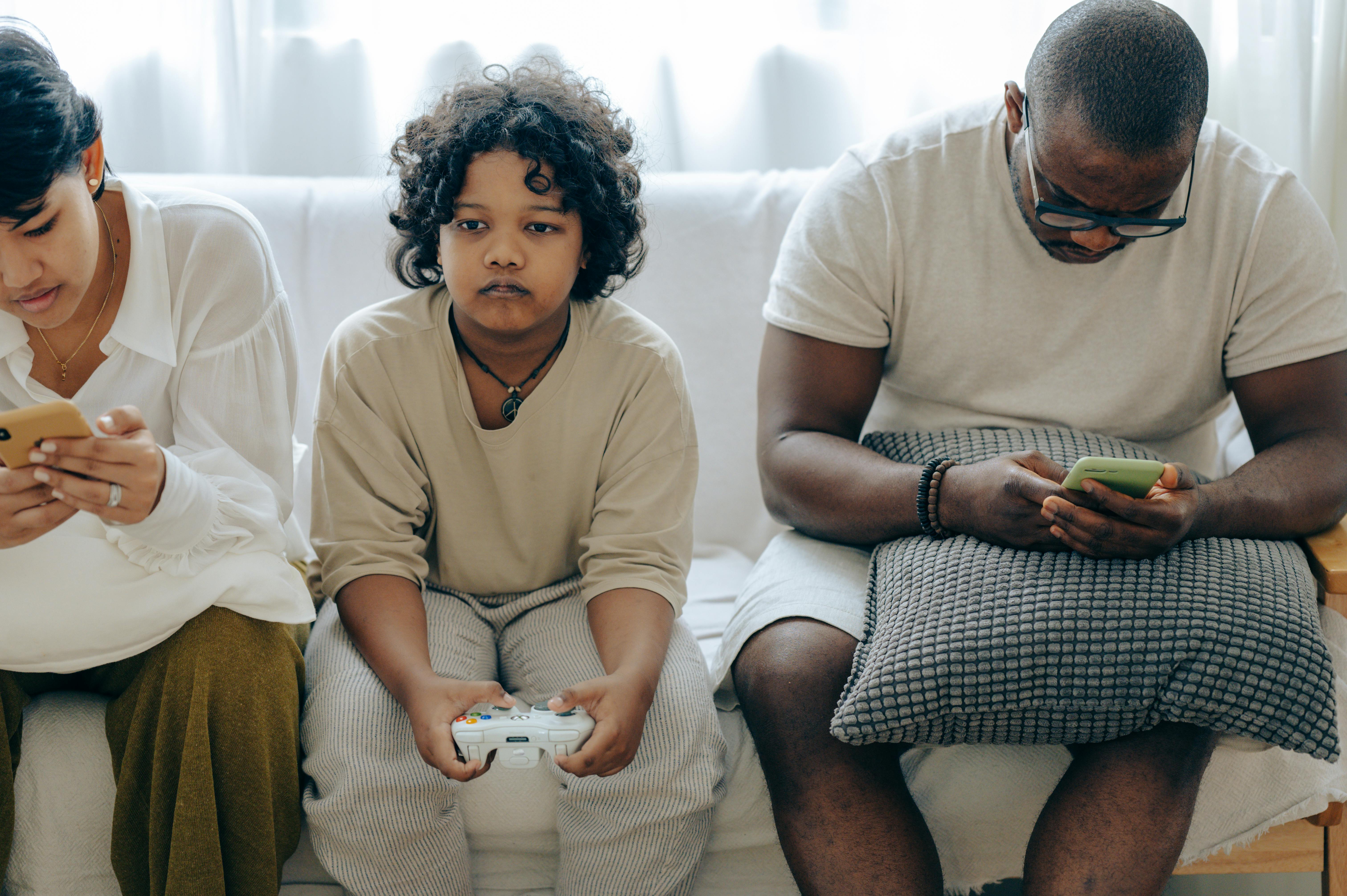 multiethnic family spending time together on couch with gadgets