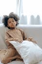 Mischievous little black girl resting on sofa with pillow