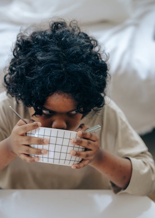 Free Curious black kid having breakfast sitting at table Stock Photo