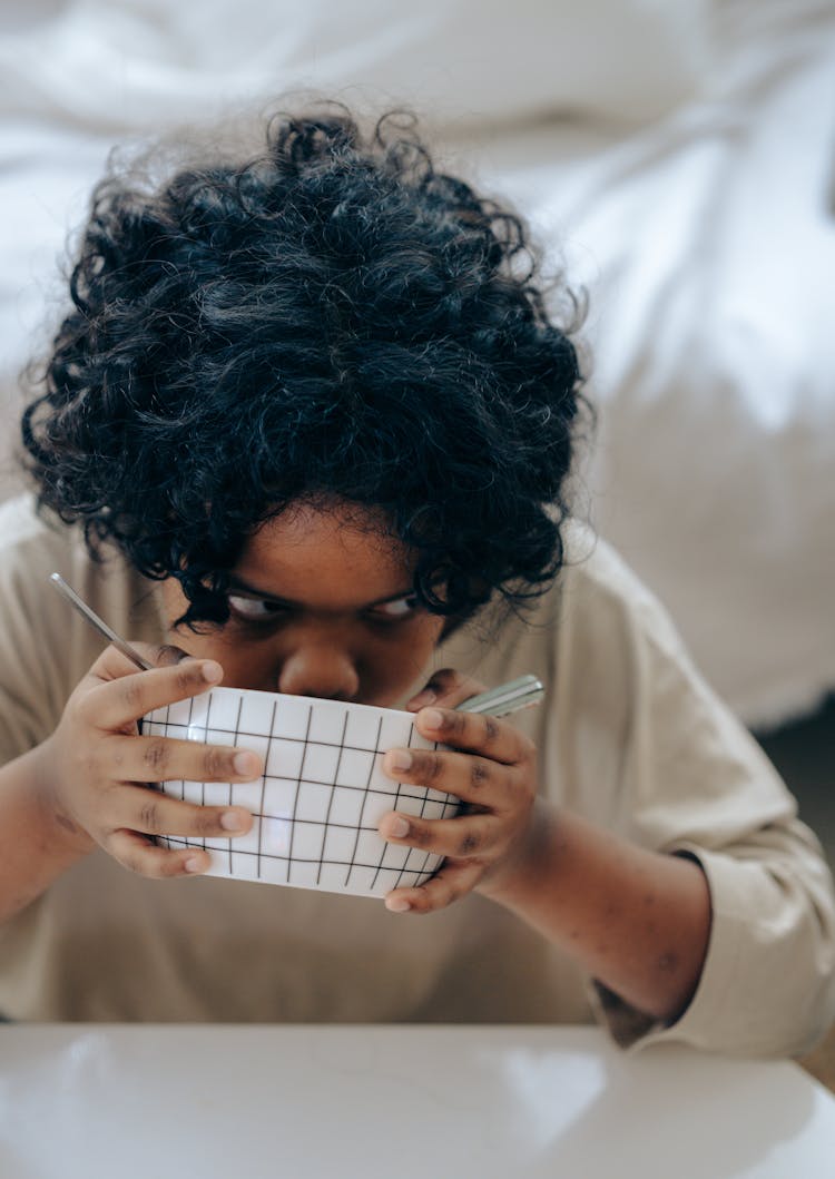 Curious Black Kid Having Breakfast Sitting At Table