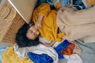 Cute little African American child lying on stack of clothes