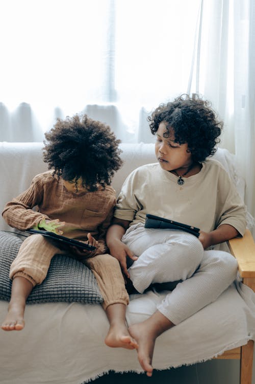 Little girls spending time together at home with tablets