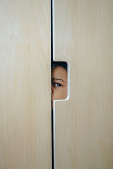 一个孩子好奇地从壁橱门后窥视着室内