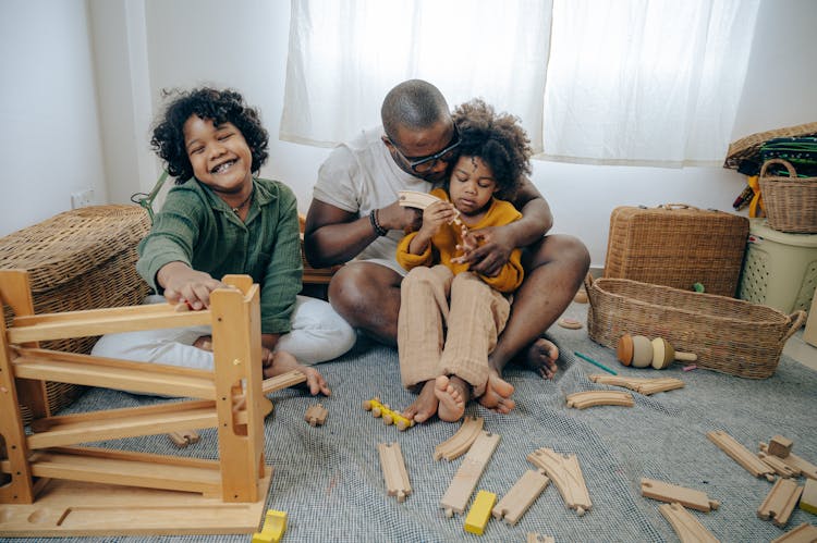 Happy Black Father And Daughters Assembling Constructor On Floor