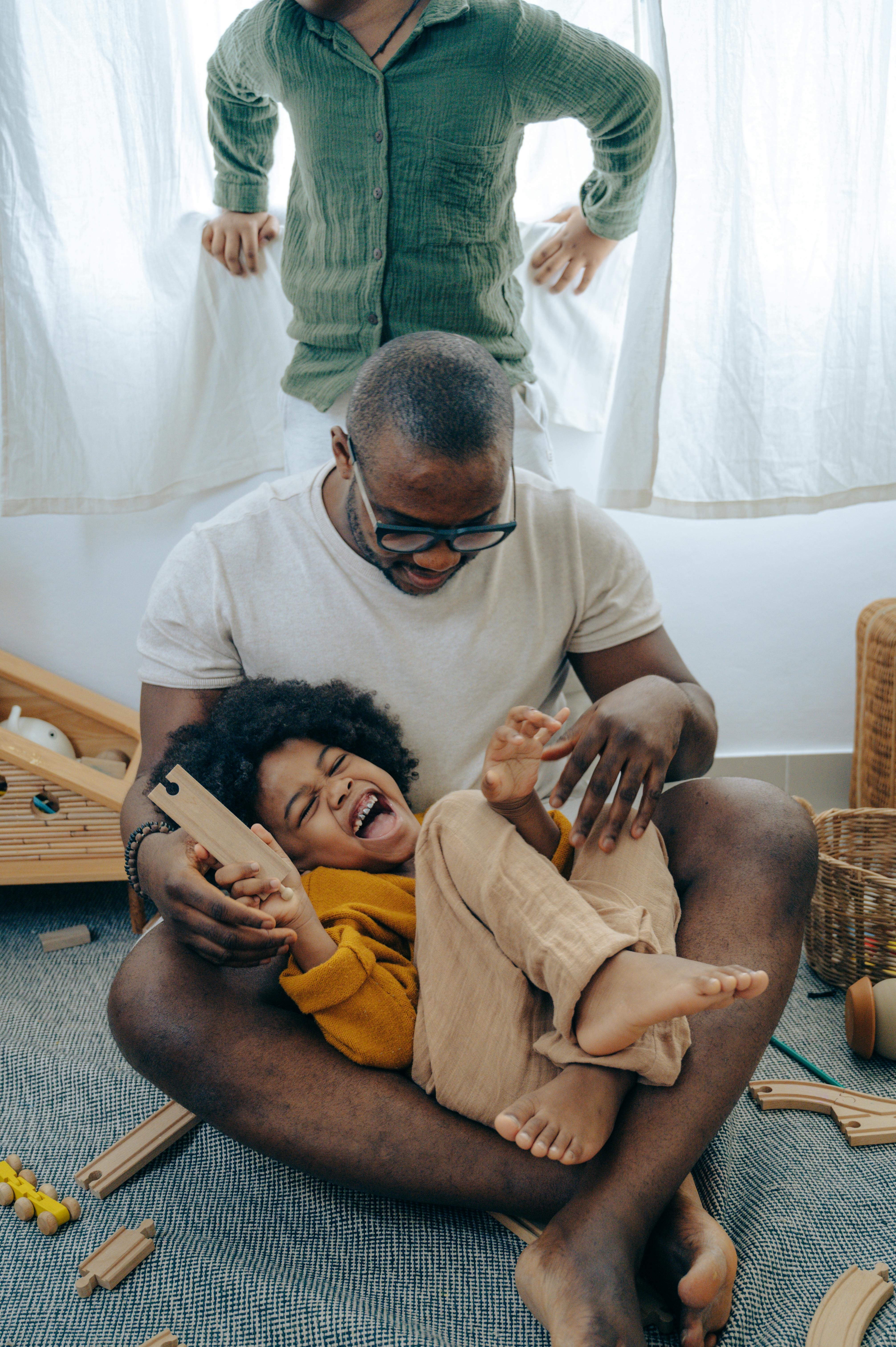 cheerful little black girl laughing during game with father