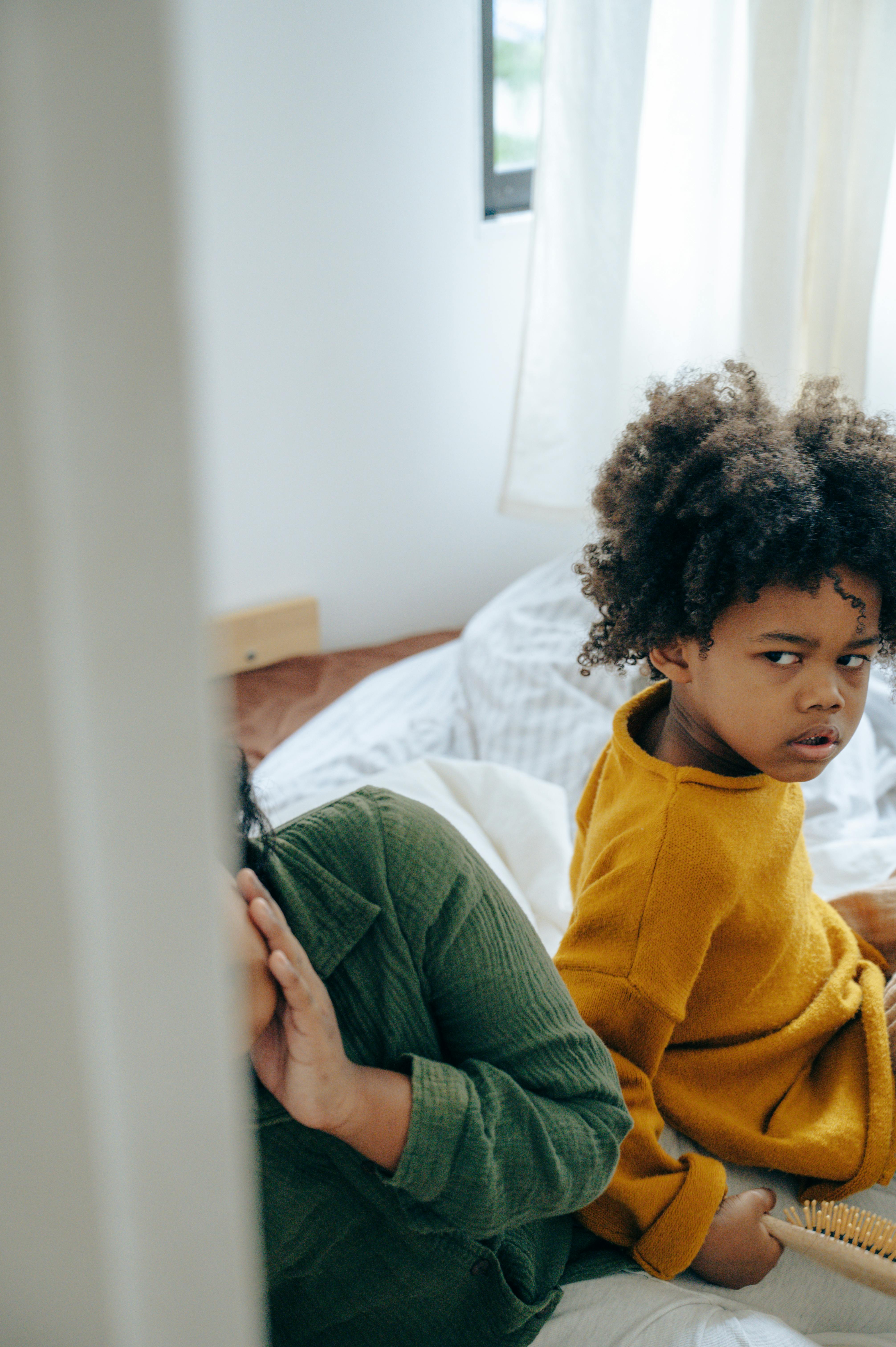 offended little girl sitting on bed with sibling