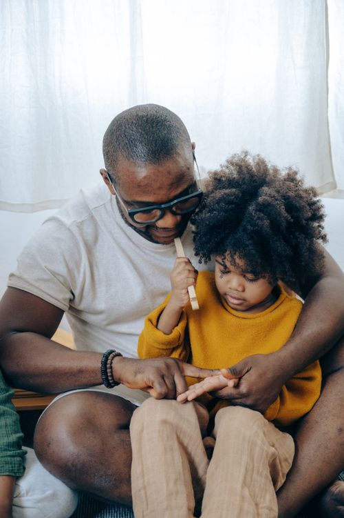 Free Serious African American man in glasses with child with curly hair sitting and interacting with each other Stock Photo