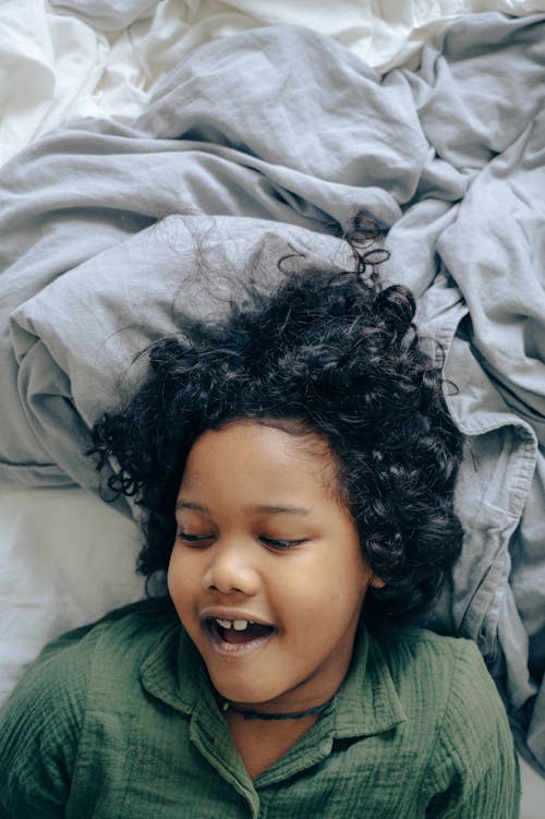 Happy black child lying on bed