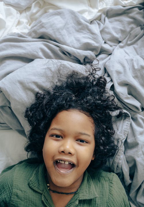 Cheerful black child lying on bed