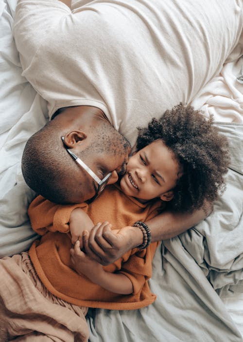 Free Father kissing child and lying on bed Stock Photo