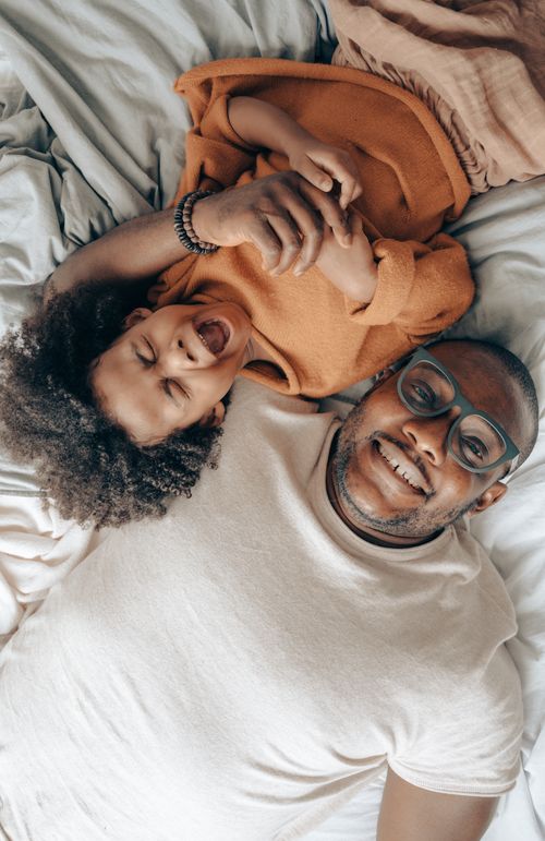Free Top view of delighted African American man and cute child in casual wear cuddling and laughing while having fun together during weekend Stock Photo