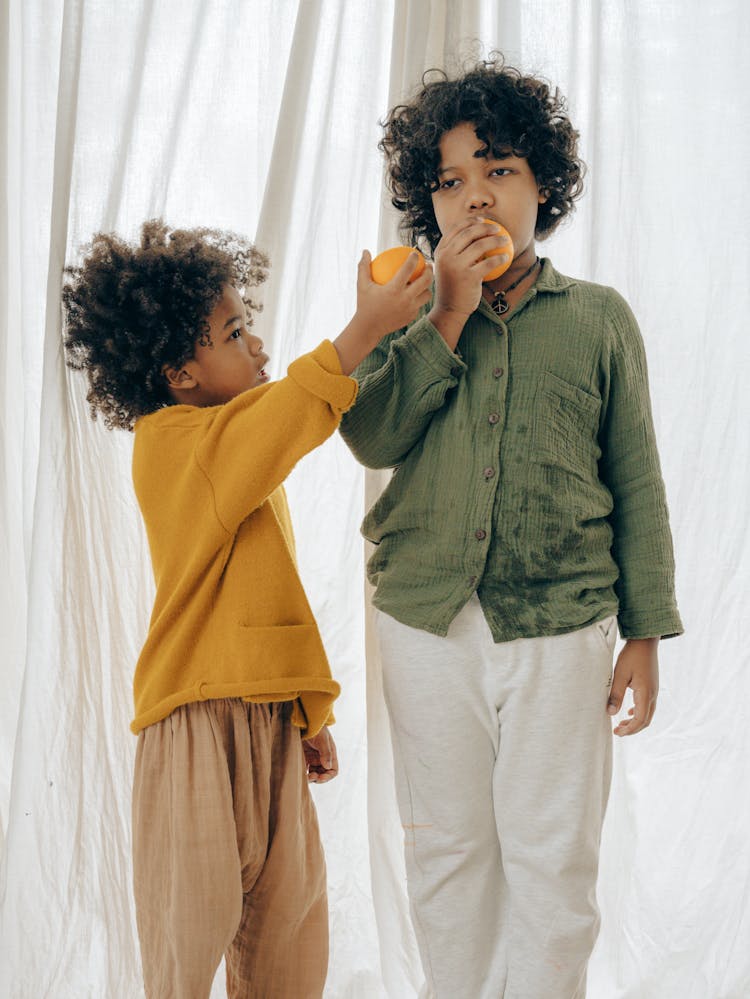 Black Siblings With Fruit In Hands At Home