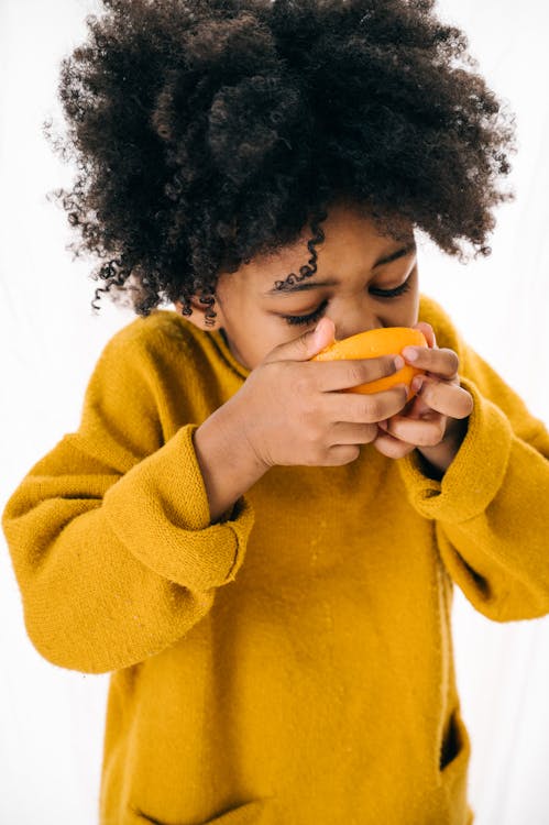 Cute ethnic child with fresh citrus on white background