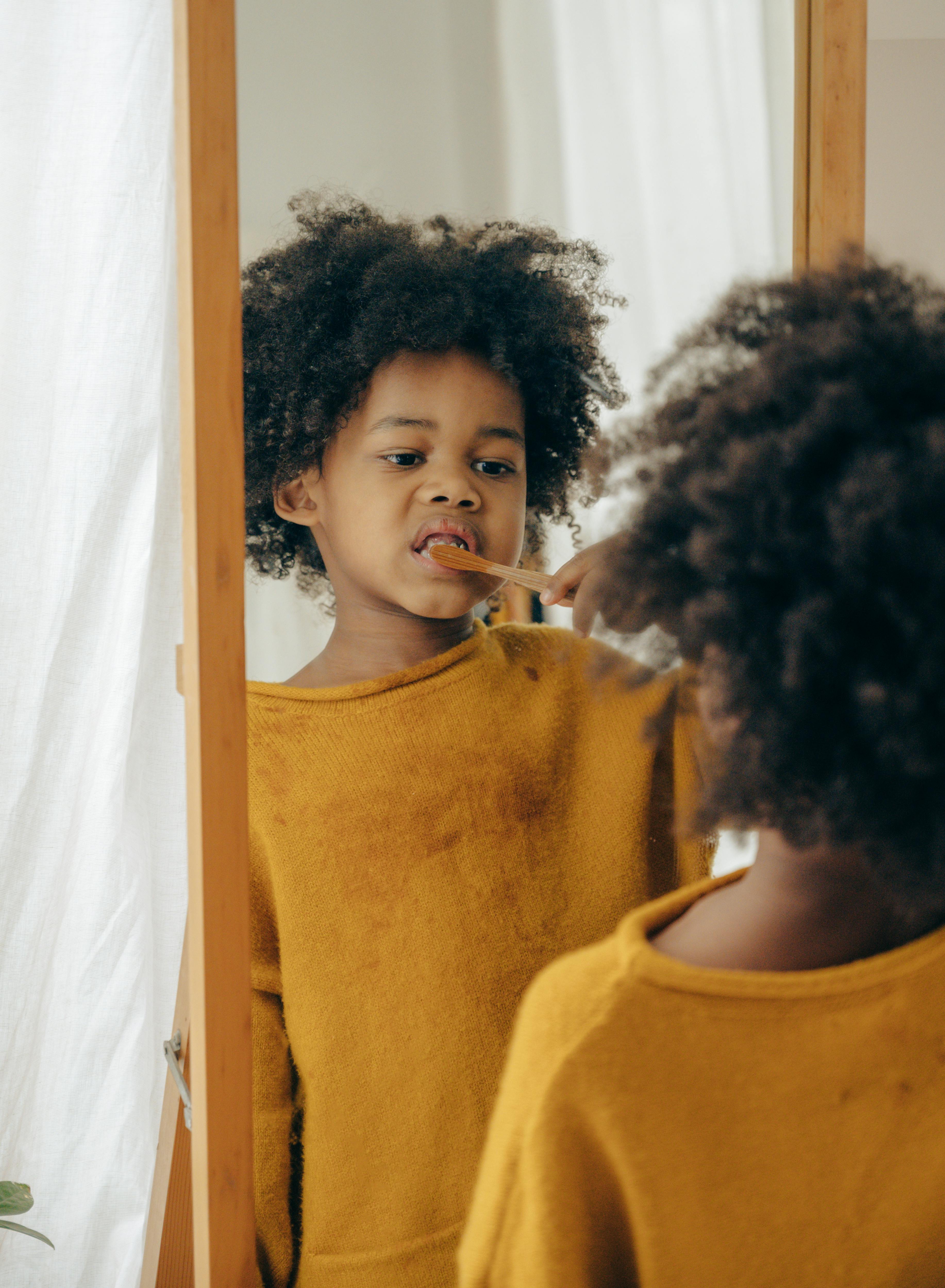 cute black kid with toothbrush in bathroom