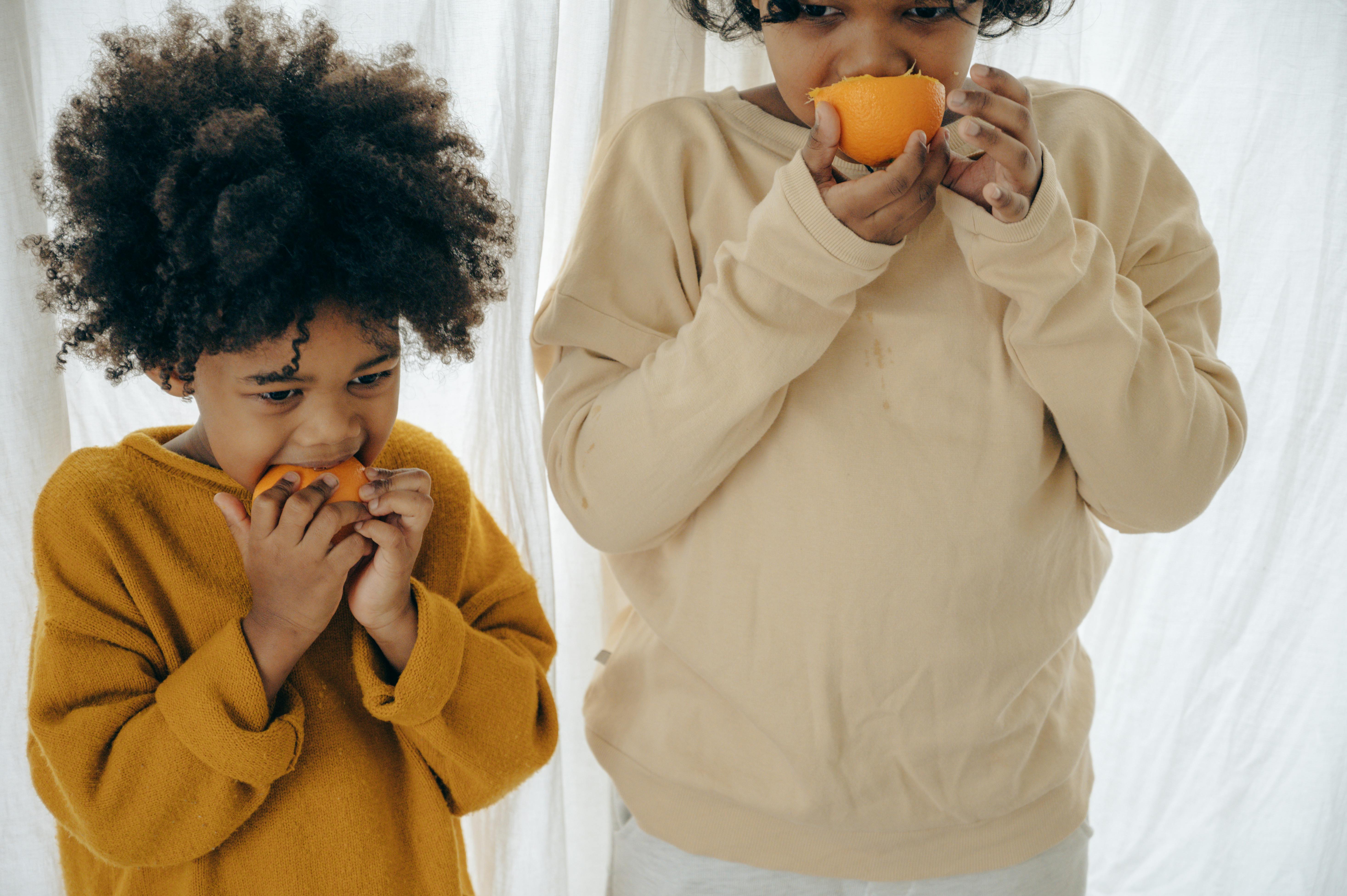 Ethnic children eating oranges on morning · Free Stock Photo