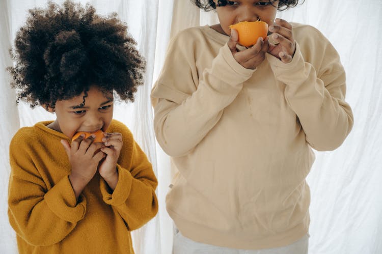 Ethnic Children Eating Oranges On Morning