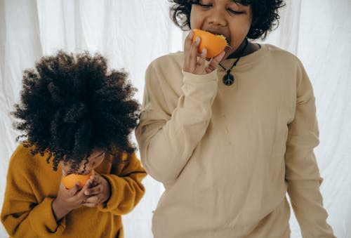 Hungry ethnic kids with fresh fruit in studio