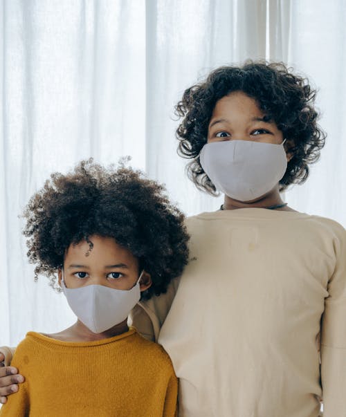 Ethnic children in medical mask against curtain